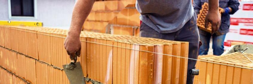 Ein Bauarbeiter setzt einen Ziegelstein 