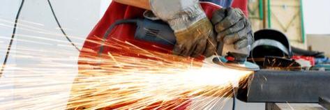 Ein Schlosser flext ein Stück Metall, sehr starker Funkenflug