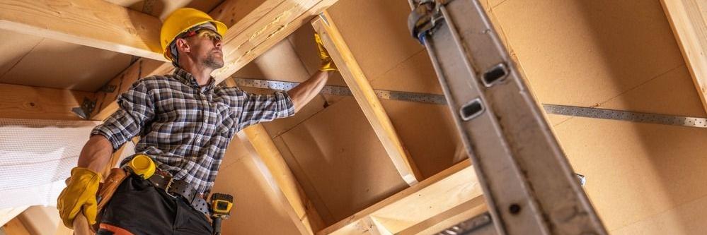 Ein Zimmermann überprüft das Dachgebälk eines Hauses