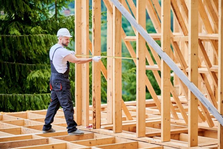 Ein Zimmermann überprüft die Konstruktion eine Holzbaus