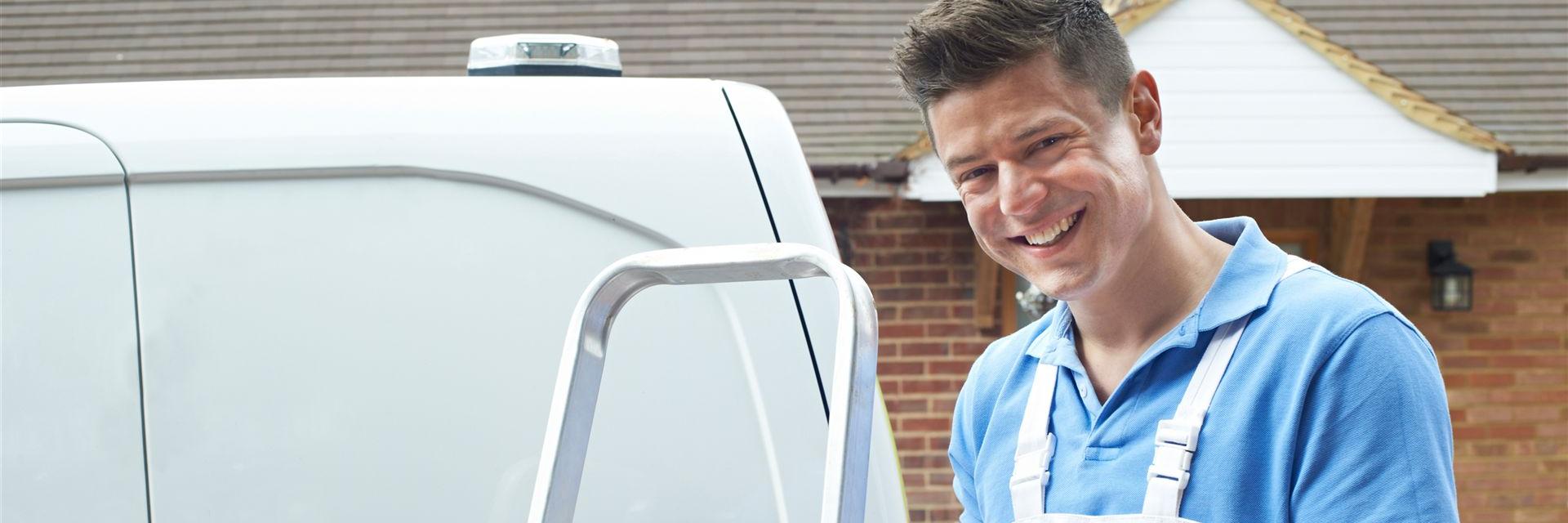 Freundlicher Handwerker steht vor seinem Bus und lächelt in die Kamera